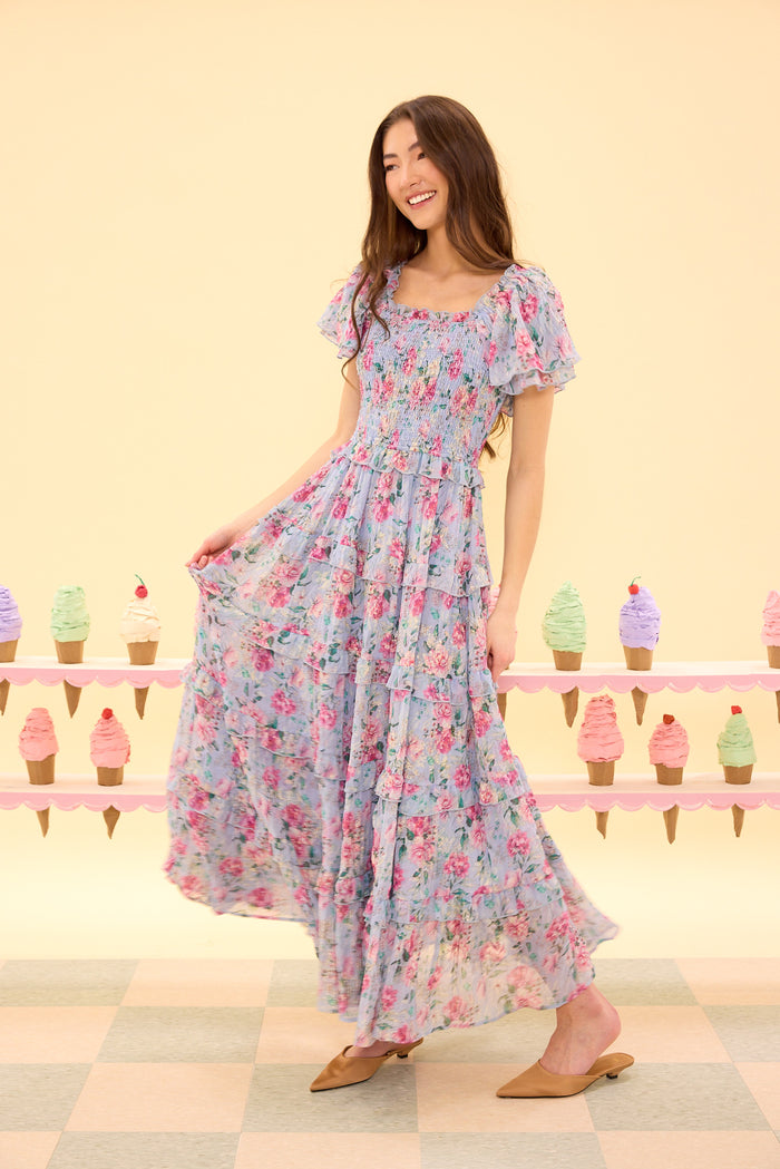 Woman wearing a floral dress standing in front of a pastel-colored ice cream cone display.