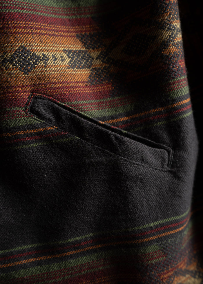 Close-up of a wool jacket pocket with a colorful, geometric pattern in red, green, and orange hues.