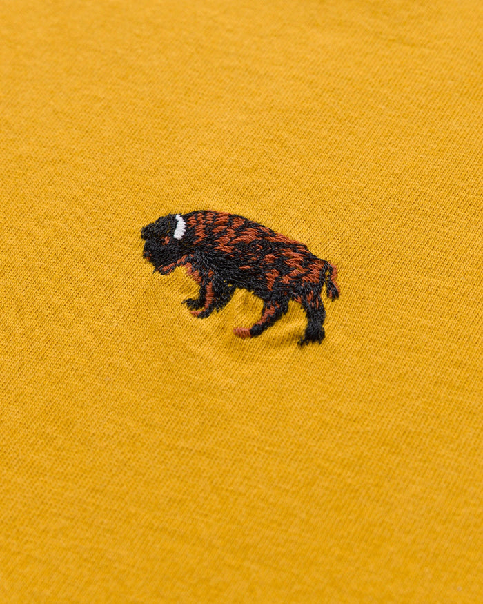Close-up of a brown and black bison embroidery on the mustard yellow tee