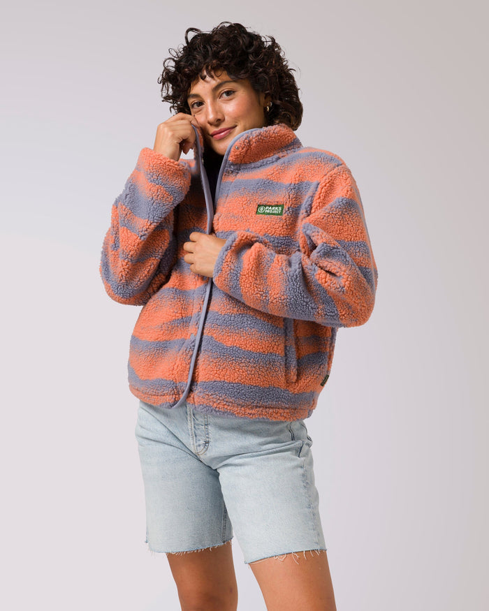 Model wearing Women's Smoky Mtn. Haze High Pile Fleece Jacket in coral and gray stripes with Parks Project patch on the chest.
