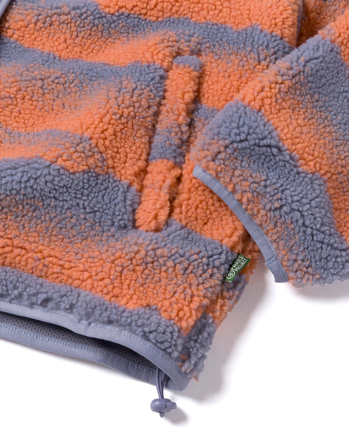 Close up of orange and gray striped high pile fleece fabric with a drawstring toggle