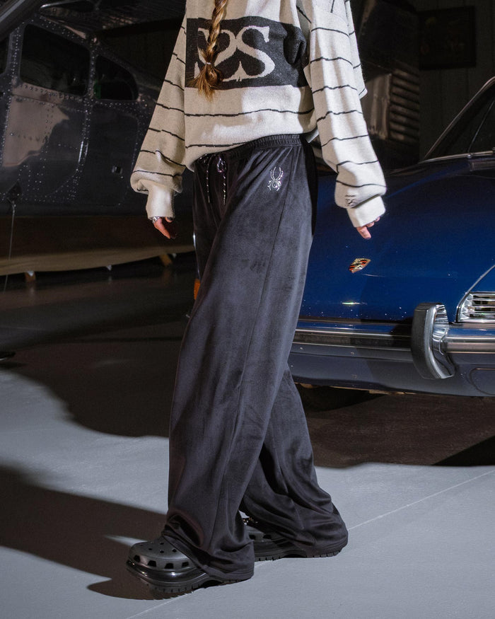 Person wearing a striped sweater and black pants standing in front of a vintage car.