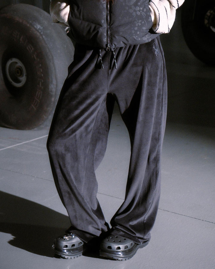 Person wearing dark pants and shoes in a garage setting with a tire in the background