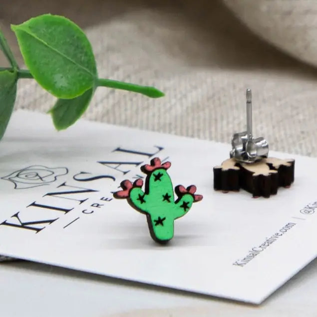 Wooden blooming saguaro earrings featuring a green cactus with pink flowers on a white display card.